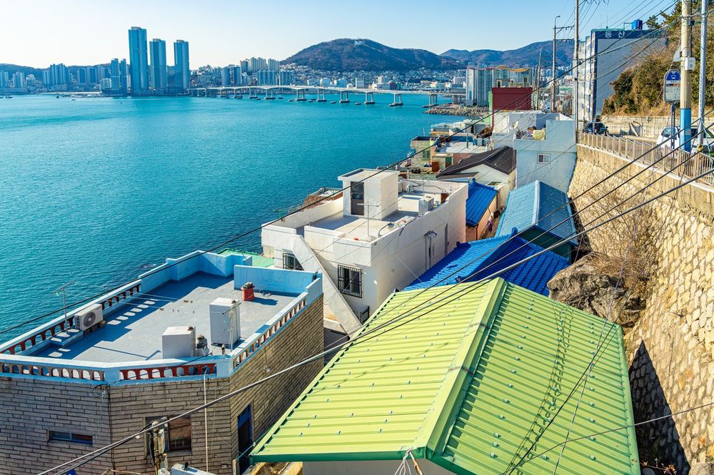 흰여울문화마을을 높은 곳에서 내려다본 전경. 절벽에 다닥다닥 붙은 집들 너머로 남항대교와 부산 도심 스카이라인이 보인다.