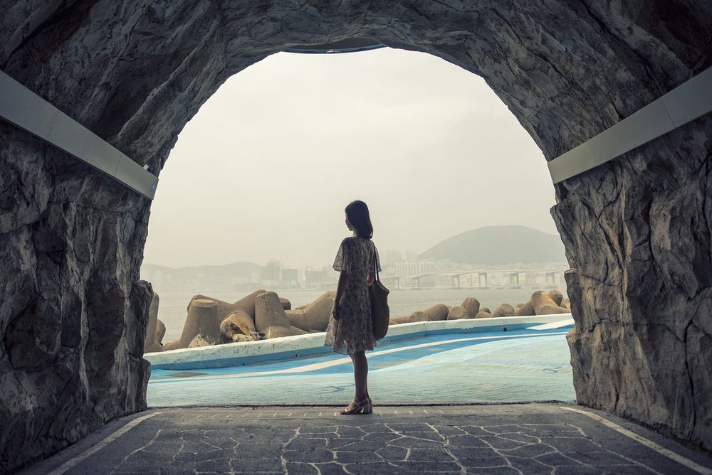 흰여울 해안터널 안에서 바라본 바다와 방파제, 그 앞에 서 있는 사람의 뒷모습.