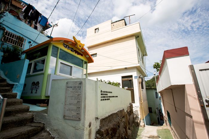 An alley lined with pastel-colored houses and a small information booth.