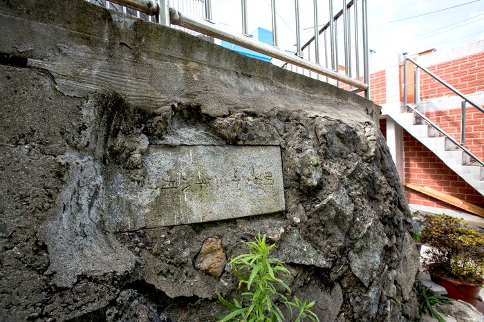 A tombstone slab set into a wall, with steps leading up above it.